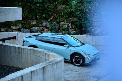 Kia EV4 parked within a circular concrete ramp structure, surrounded by stone walls and dense green foliage