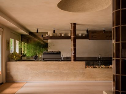 A subtly veined beige stone forms a coffee counter, while a hand-plastered dome sits overhead