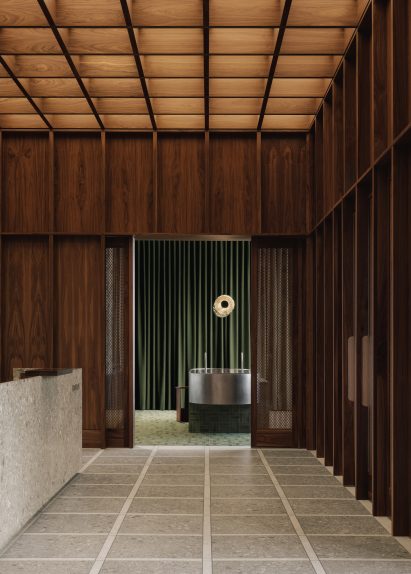 A grid created by walnut panelling continues on a coffered ceiling and across terrazzo flooring