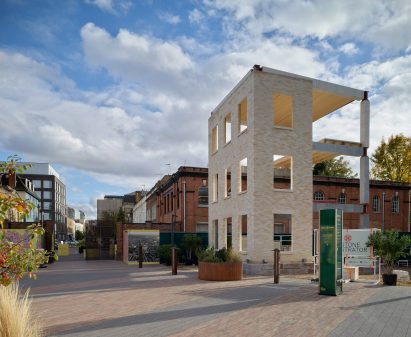 Photo of a partly built housing block demonstrating different natural stone materials, surrounded by finished housing and urban buildings