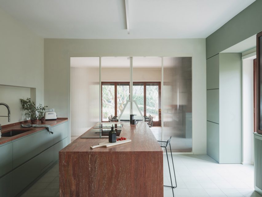 Mint-green kitchen with red travertine island in revamp of 1960s villa by StudioTamat