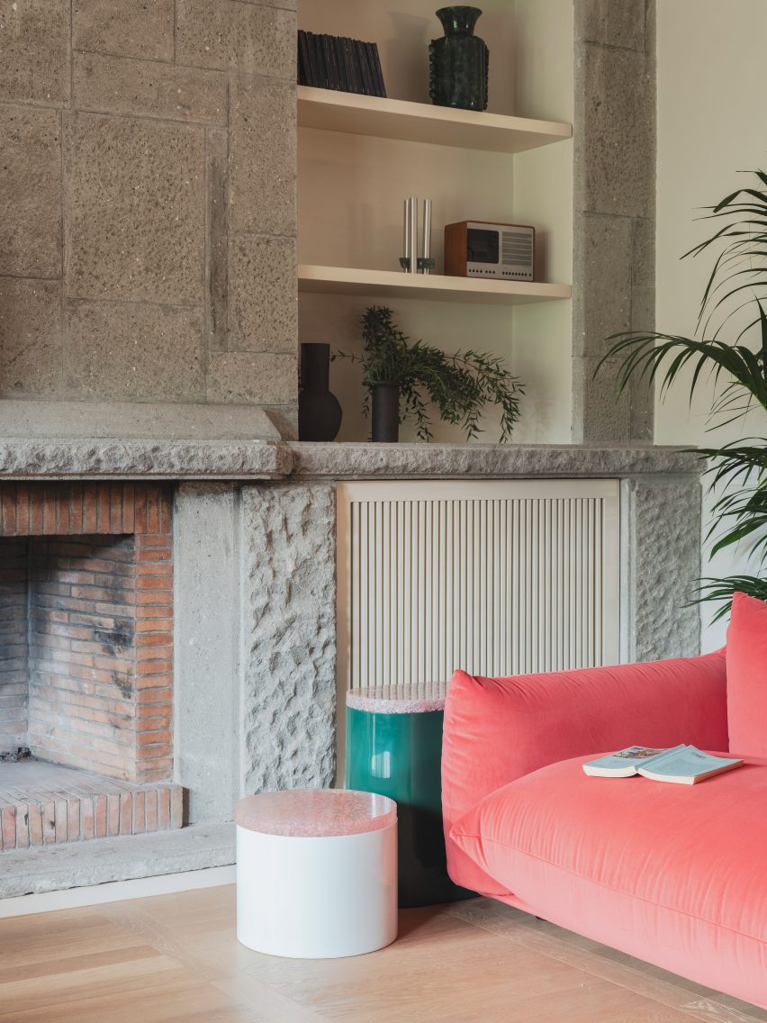 Living room with pink sofa and stone fireplace in revamp of 1960s villa by StudioTamat