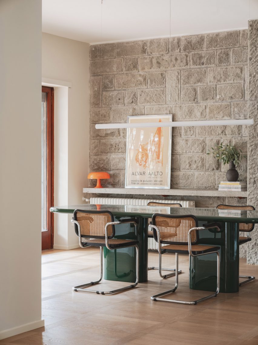 Dining room with stone wall in revamp of 1960s villa by StudioTamat
