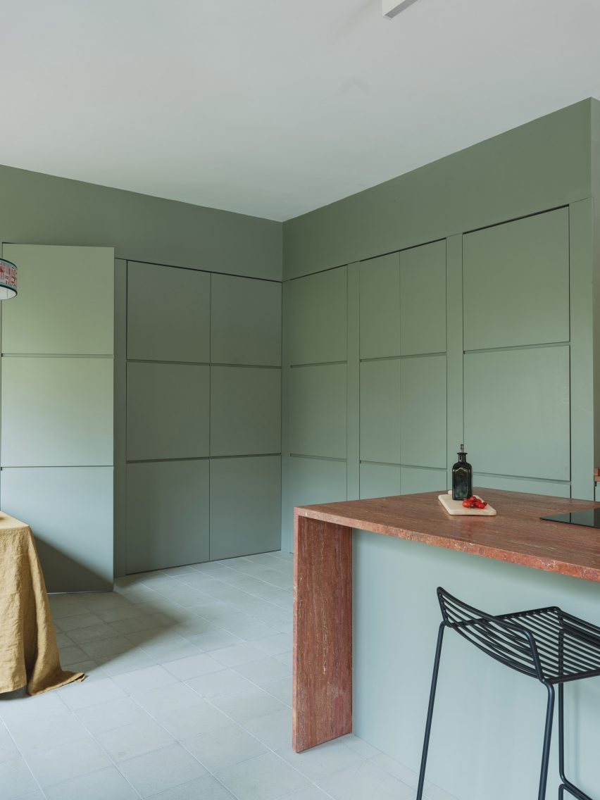 Mint-green kitchen with red travertine island in revamp of 1960s villa by StudioTamat
