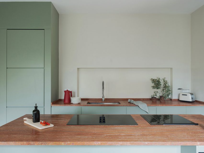 Mint-green kitchen with red travertine island in revamp of 1960s villa by StudioTamat