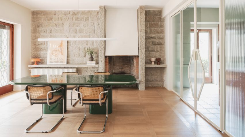 Dining room with stone wall in revamp of 1960s villa by StudioTamat