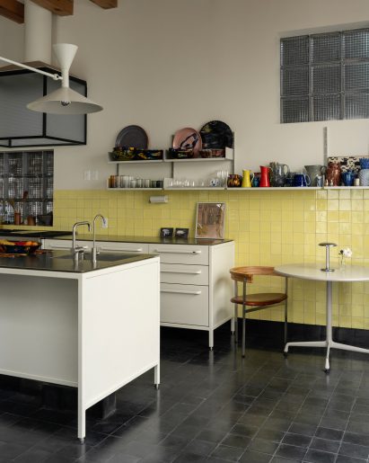 A kitchen with yellow wall tiles and metal fixtures