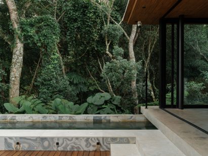 A swimming pool extends from one end of a modular building