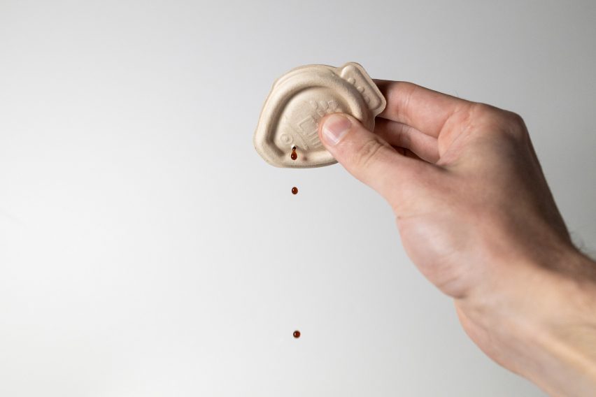 Photo of a hand holding the Holy Carp! fish packaging and squeezing it upside down so small droplets of soy sauce come out
