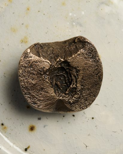 Close-up of bronze peach paperweights by Luca Guadagnino for JW Anderson
