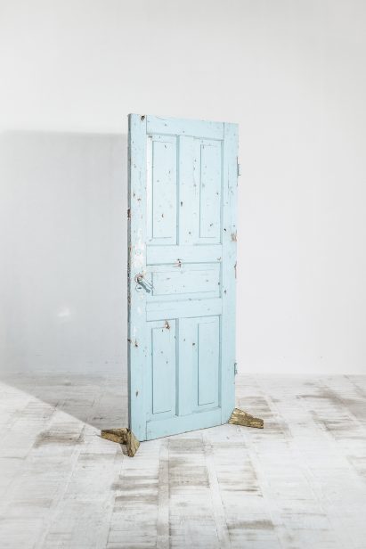 Door propped up by brass feet made from recast shell casings
