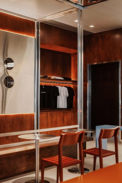 Stainless steel tables, framing and wall panels contrast stained plywood within a restaurant interior