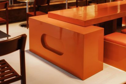 The top of a custom orange table supported on a cuboid block at the end