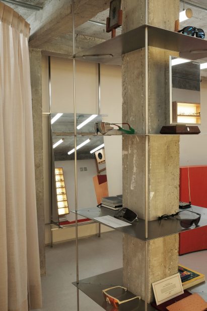 Thin metal shelves suspended on thin rods around a concrete column