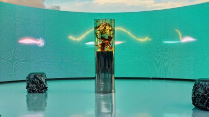 Daytime view of the Plant Pulses installation with a curved turquoise LED screen framing the resin sculpture on Miami Beach
