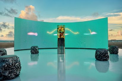 Close view of Marcin Ruskin's resin sculpture containing botanical material set against a turquoise digital backdrop