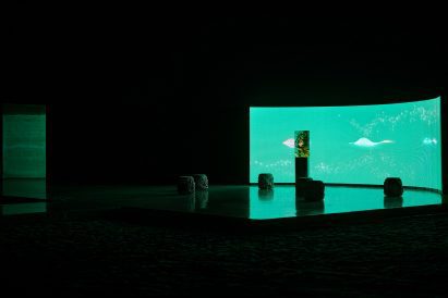 Large curved LED screen showing abstract pink light forms behind a central illuminated resin sculpture by Marcin Ruskin for Perrier-Jouët
