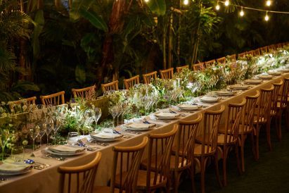 Long dinner table set within tropical foliage for Perrier-Jouët’s Banquet of Nature event