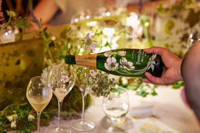 Perrier-Jouët champagne being poured into floral-etched glasses on a botanically decorated table