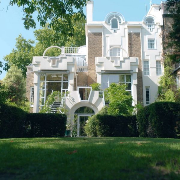 Front view of The Cosmic House in west London, framed by trees and manicured gardens