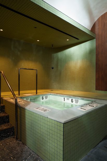 A cold plunge surrounded by two-inch-square green tiles
