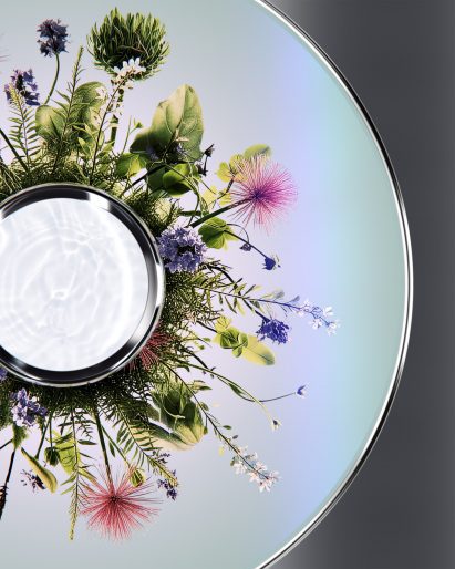 Flatlay image of the Cognitive Bloom device, showing a chrome disc containing a blooming virtual garden, seeming to spread outwards from a smaller disc in the centre of the larger one