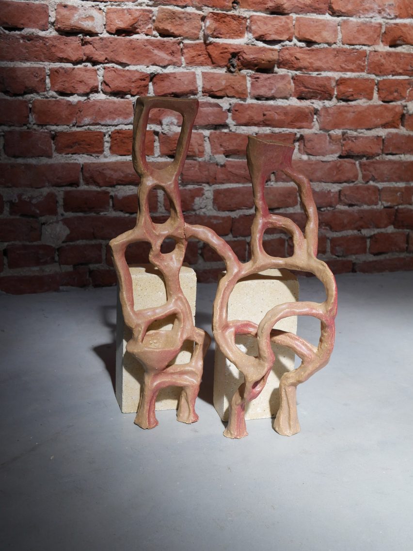 Photo of a complex ceramic sculpture made of coils of clay forming two abstracted, conjoined figures, with a pale red glaze