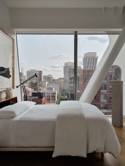 Bedroom with an angled glass wall overlooking Lower Manhattan
