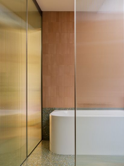 Bathroom with earth-hued tiles, terrazzo and fritted glass