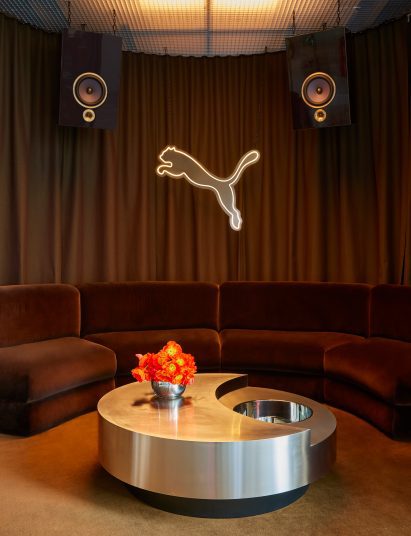 The Puma logo illuminated against curtains that surround a lounge area