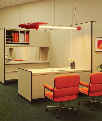 Pen-shaped lamp suspended from the ceiling in a retro-style office