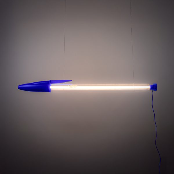 Pen-shaped lamp suspended in front of grey backdrop
