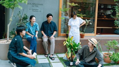 People sitting outside on a bench next to a building