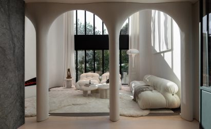 An image showing a contemporary, white living room that can be seen through curved archways.