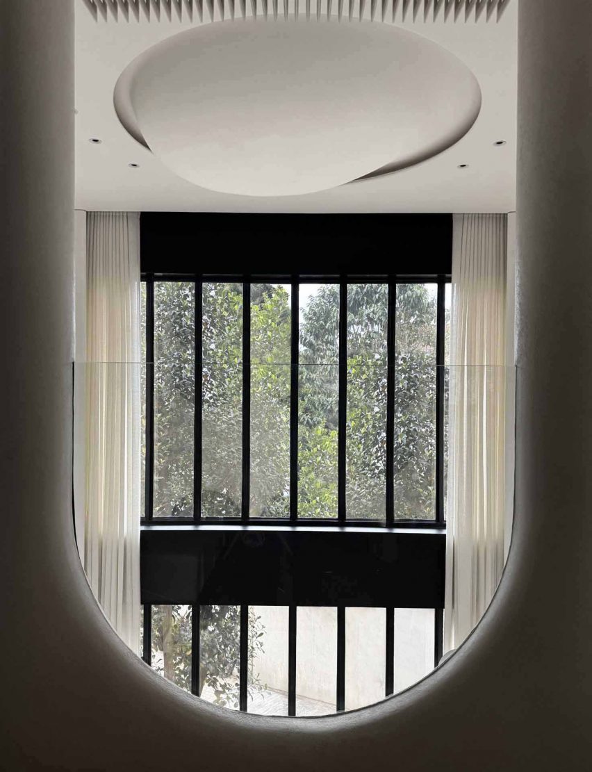 Photograph of an egg-like ceiling sculpture with tall glass windows in the backdrop.
