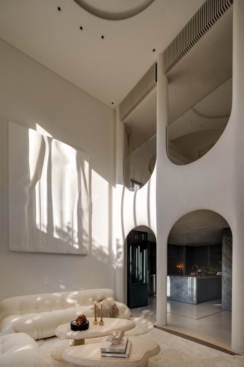 Image of a contemporary, white living room with a 3D printed artwork inspired by ocean waves, and stacked inverted arches that span two floors.