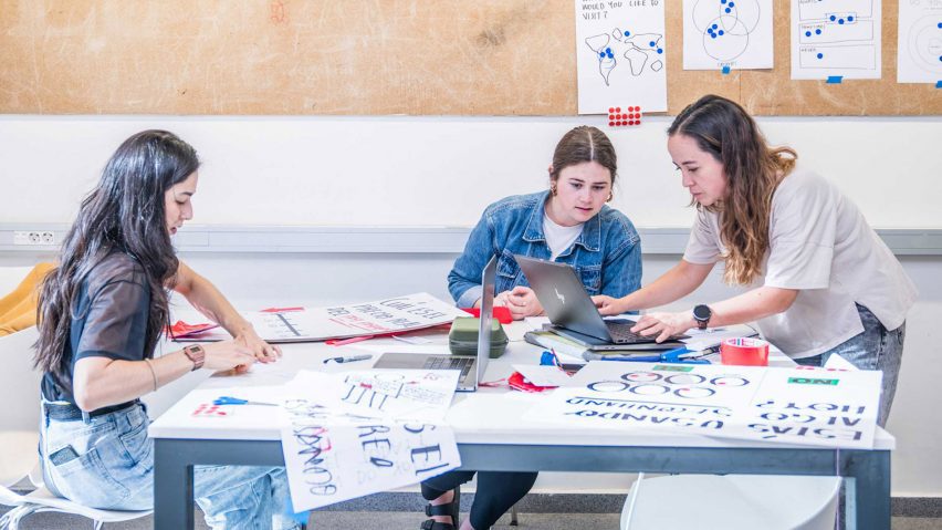 people sitting at a desk looking at drawings