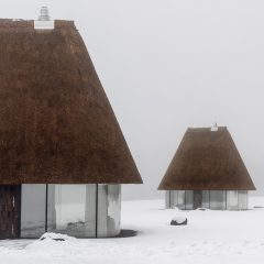Glass hut with thatched roof in snowy landscape