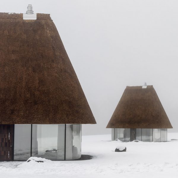 Glass hut with thatched roof in snowy landscape