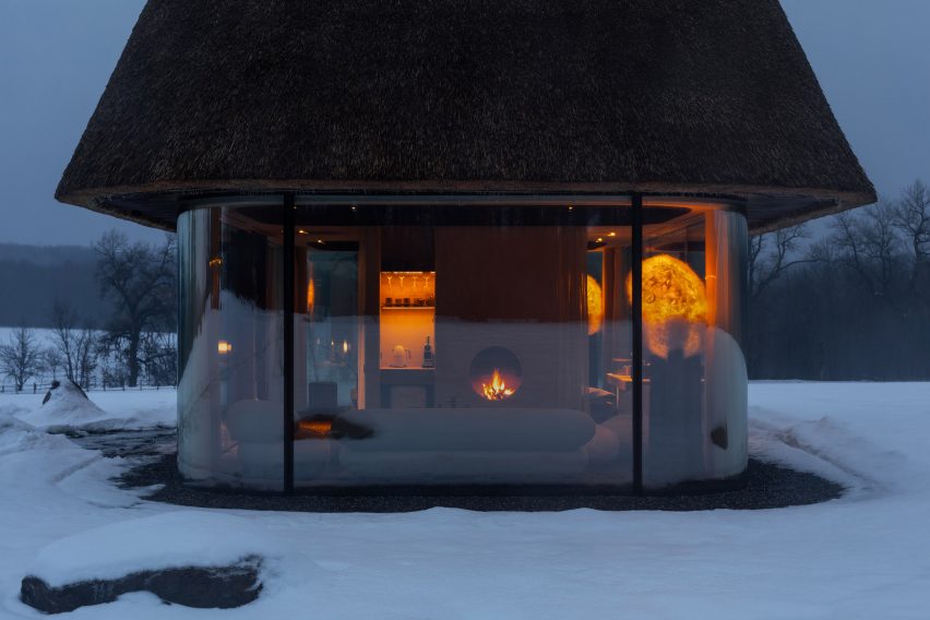 Glass hut with thatched roof in snowy landscape