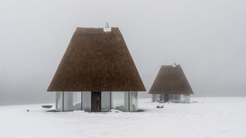 Glass hut with thatched roof in snowy landscape