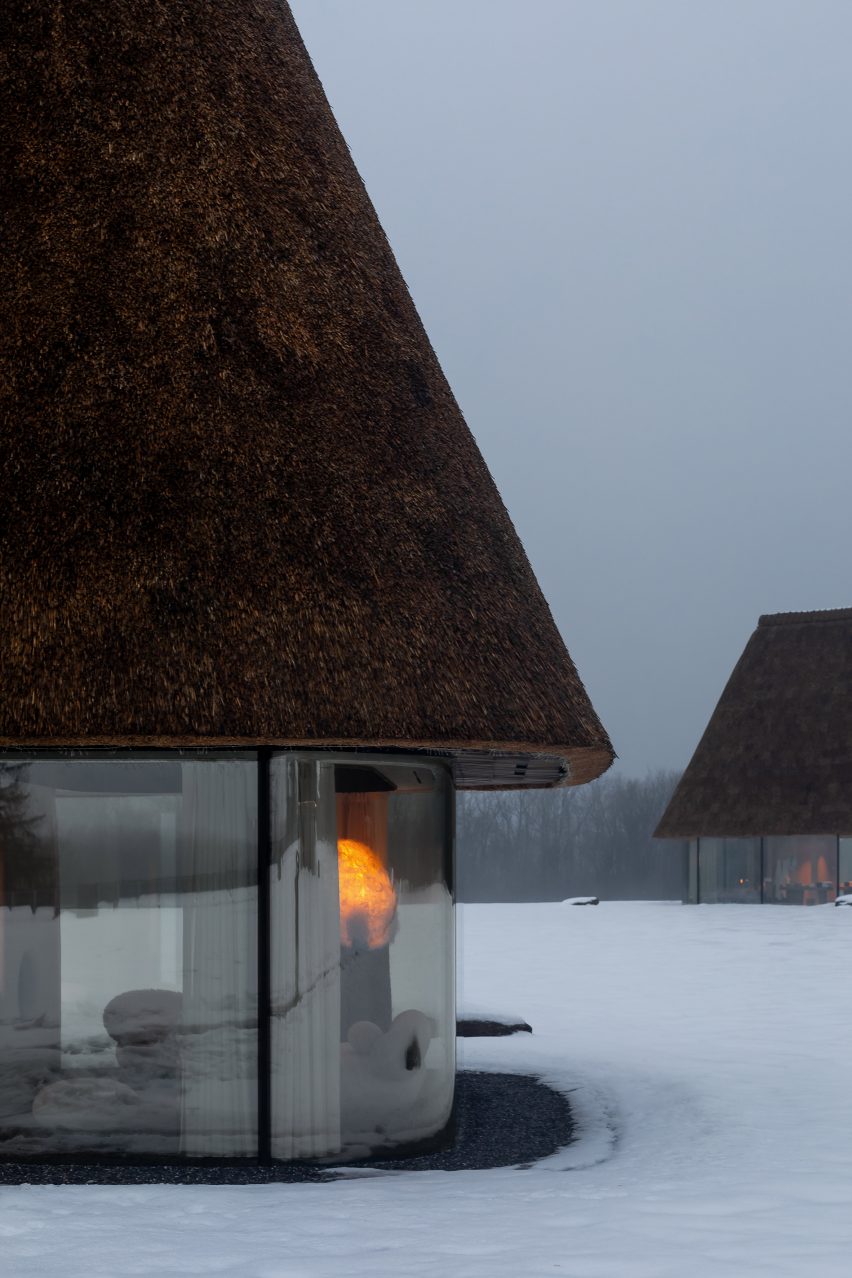 Glass hut with thatched roof in snowy landscape