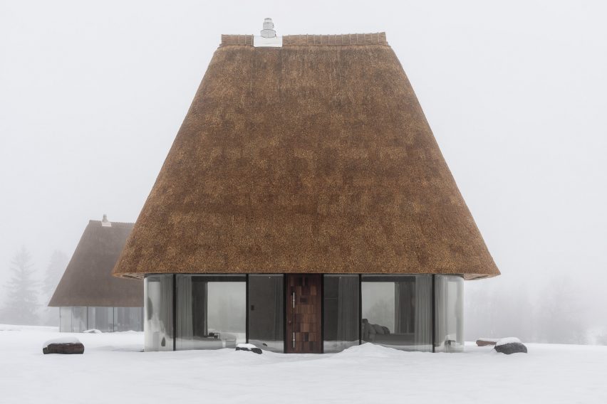 Glass hut with thatched roof in snowy landscape