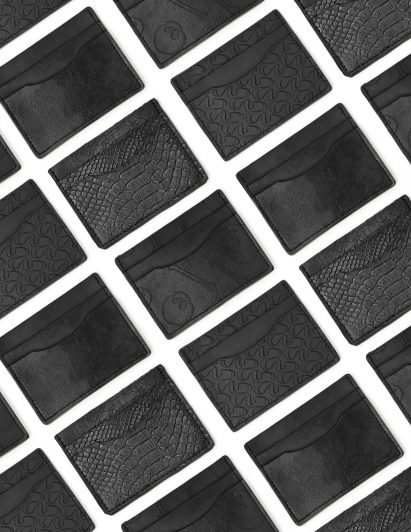 Photo of rows and rows of small card wallets made of black leather-like New Grain material debossed with different designs