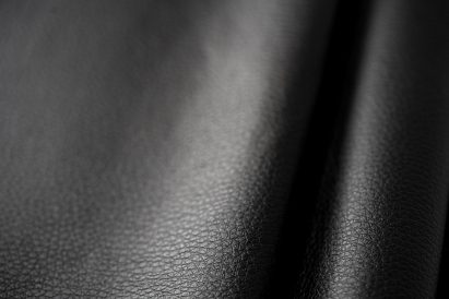 Close-up photo of Arda's New Grain material showing a soft, supple black leather-like material with a fine grain pattern on the surface