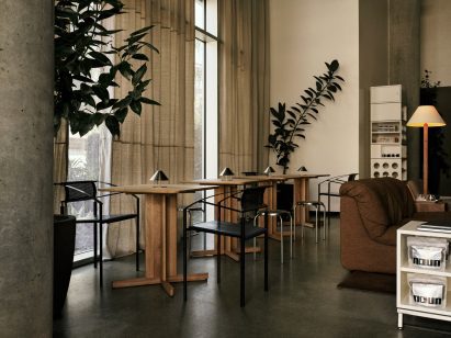 Row of wooden two-top tables beside tall curtains