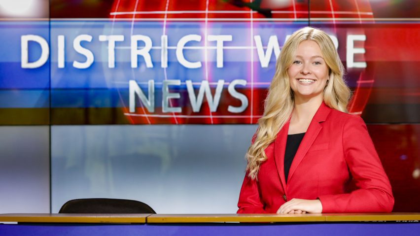 person sitting behind a news desk