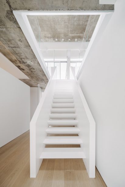 A central stairwell wrapped with glass balustrades on the upper level