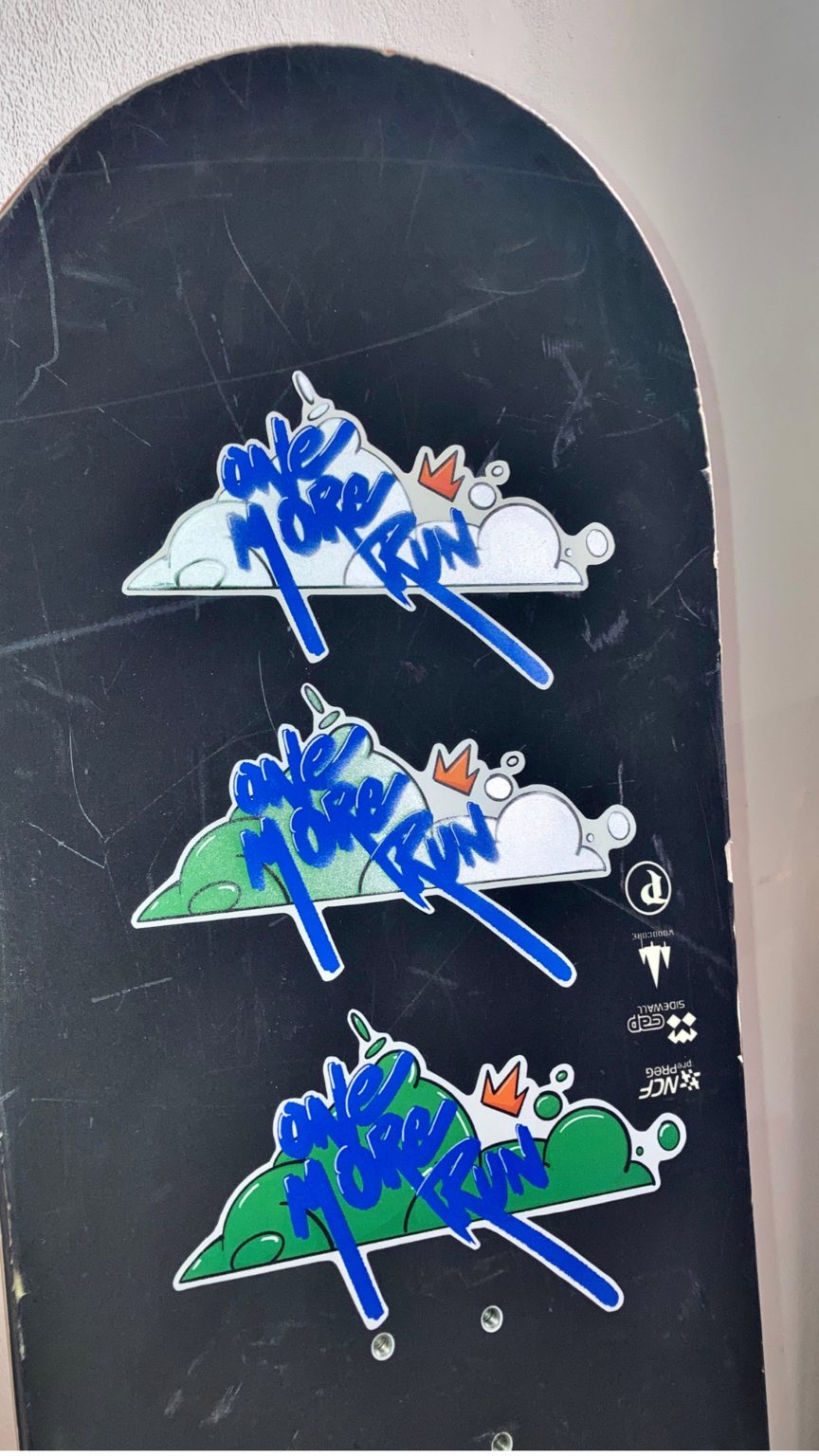 Photo of three Snow Seeds sticker prototypes on a snowboard
