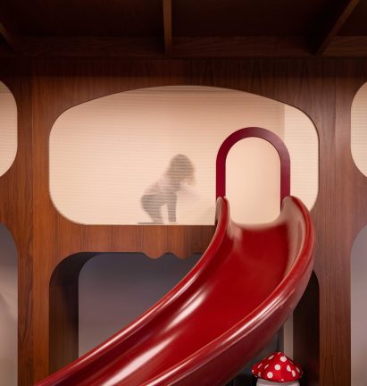 A red slide curves down from a mezzanine to the floor